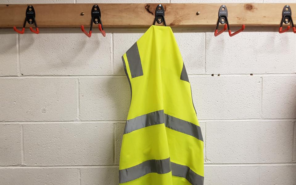 Image of a lone worker's vest hanging on a hook in locker room