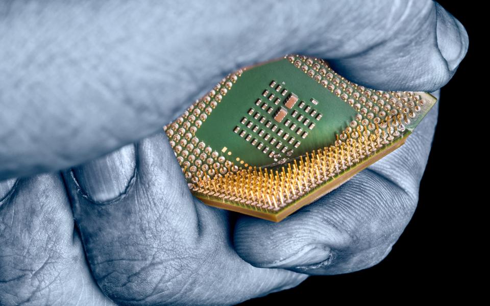 Close-up of a mysterious hand crushing a computer chip.