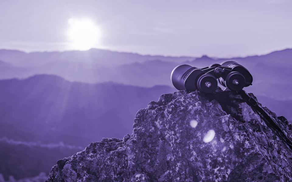 Binoculars on top of rock mountain at beautiful sunset background.