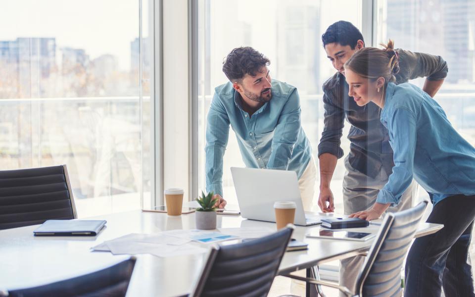 A happy business team looking at a laptop computer in a conference room.