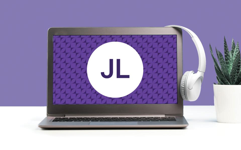Image of a laptop with a set of headphones on a desk with an amethyst color scheme.