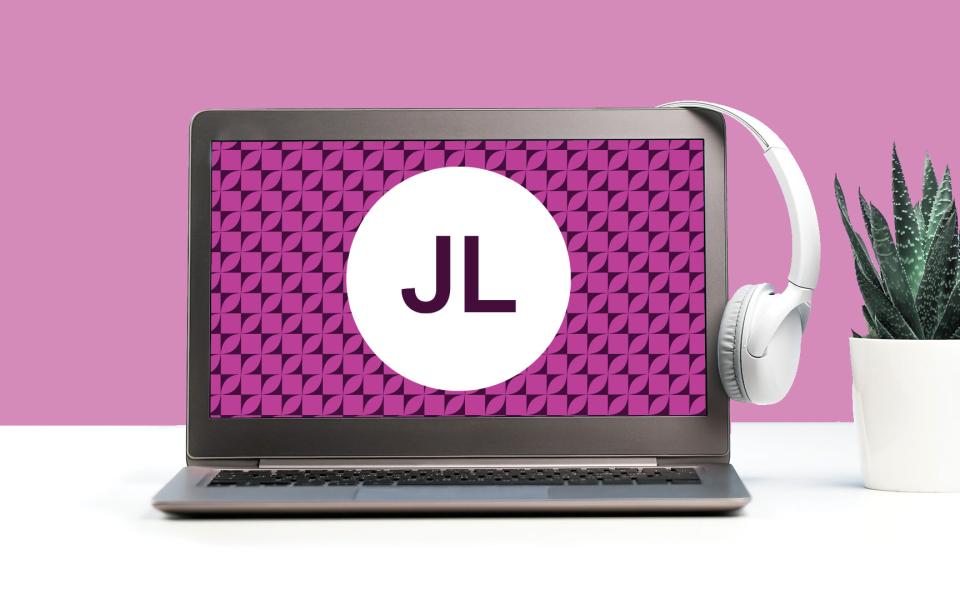 Image of a laptop with a set of headphones on a desk with a garnet color scheme.