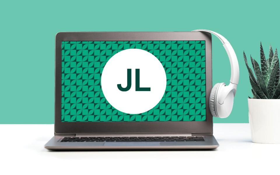 Image of a laptop with a set of headphones on a desk with a jade green color scheme.