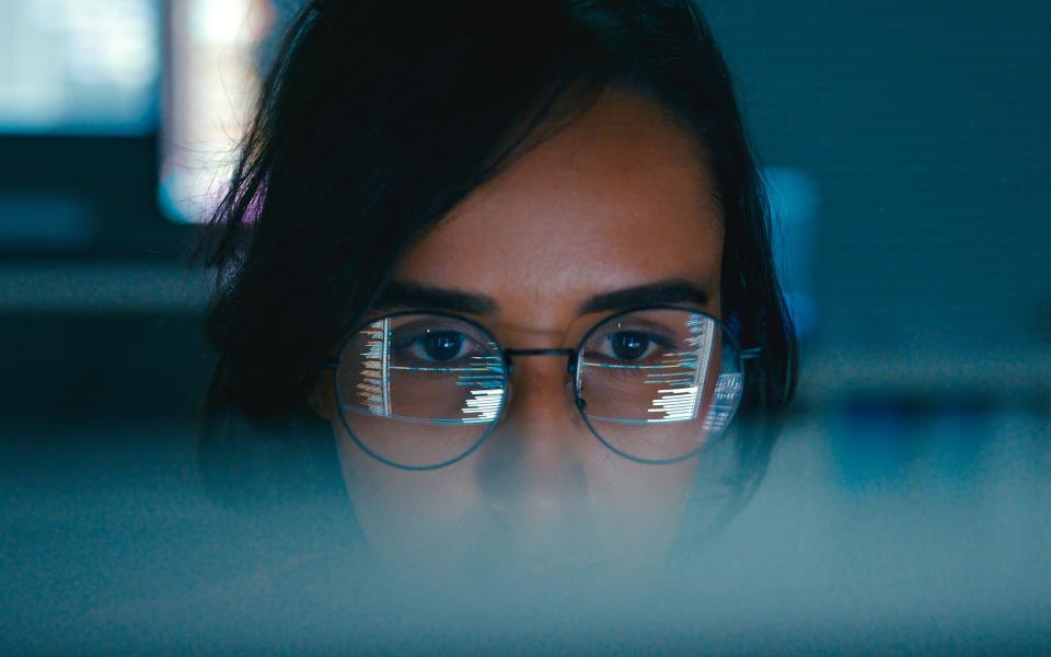 Closeup of female computer programmer with reflection of code in her glasses.