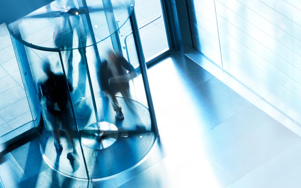 A high angle view of a people entering and exiting an office building through a revolving door