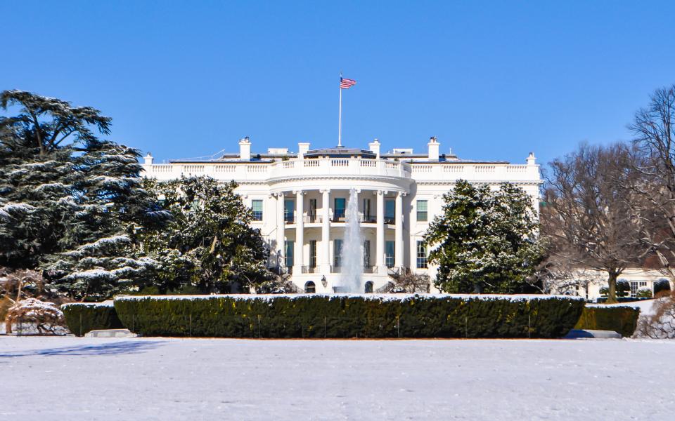 View of the snowy exterior of the White House in wintertime.