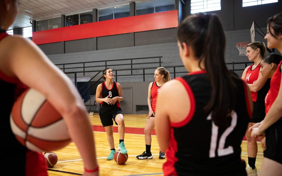 Coach giving motivational talk to women's basketball team.