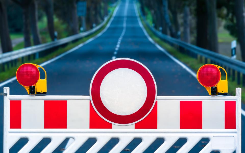 Red and white colored street barrier blocking an empty road.