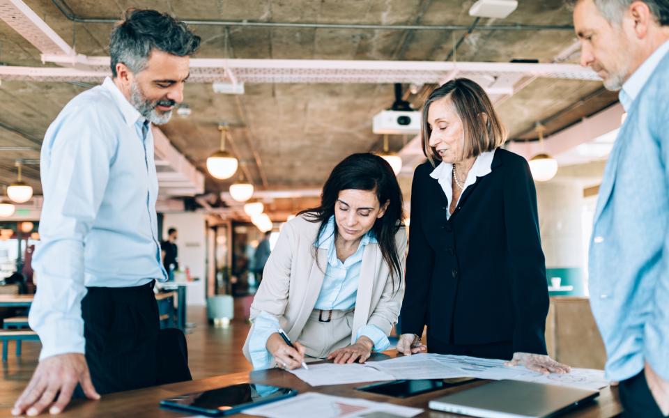Group of businesspeople around a conference table as one woman signs a document.